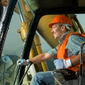 branche-baugewerbe-xs Eine Person mit Sicherheitshelm in einem Bagger