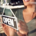 branche-franchise-xs Eine Person mit einem Öffnungsschild an der Tür